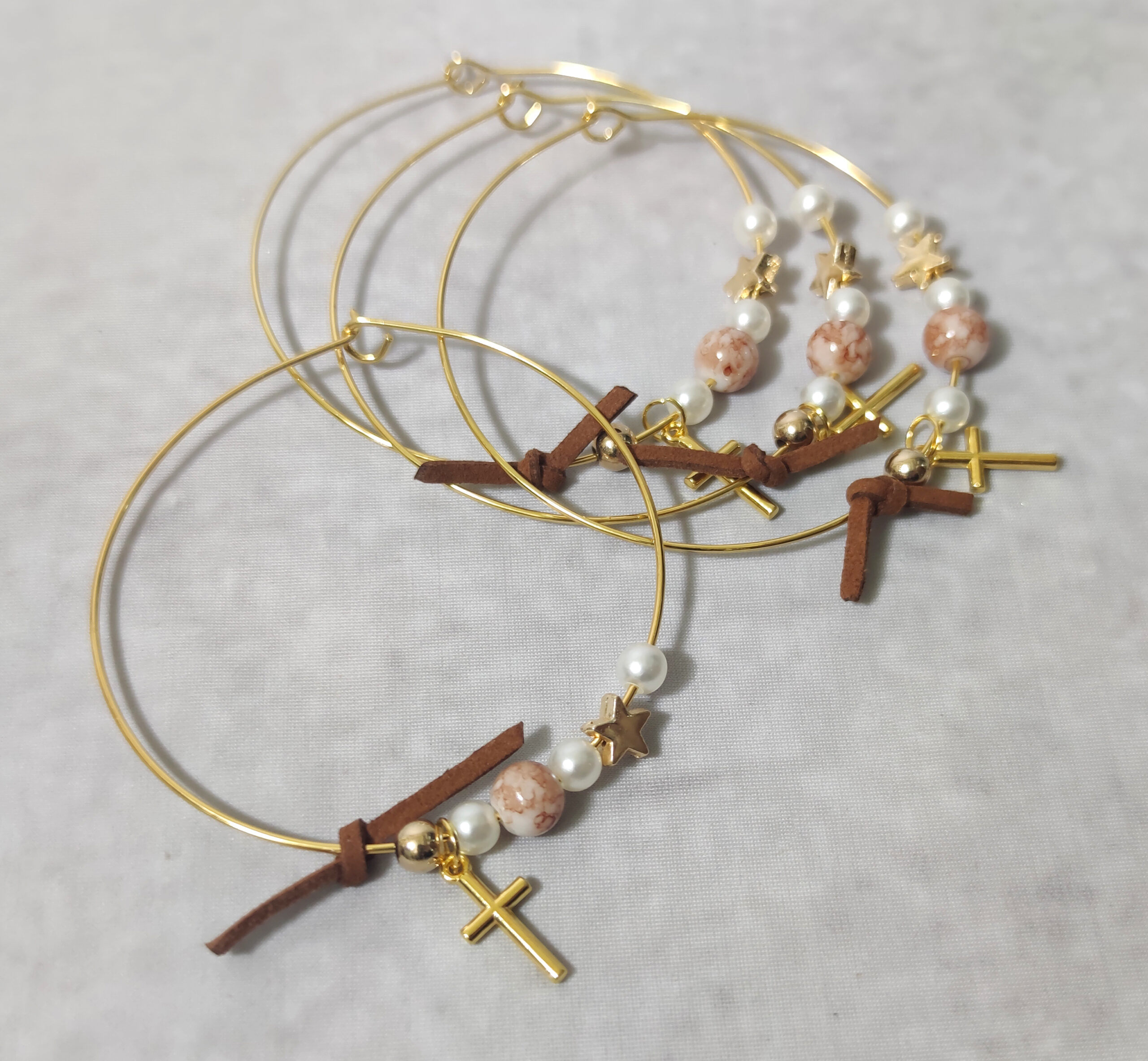 Μαρτυρικά βάπτισης μεταλλικά βραχιόλια στολισμένα με 3 λευκές πέρλες, περίτεχνη χάντρα με νερά από σοκολά απόχρωση, χρυσή χάντρα και χρυσό αστεράκι με μεταλλικό χρυσό σταυρό και δερμάτινο σοκολά φιογκάκι.