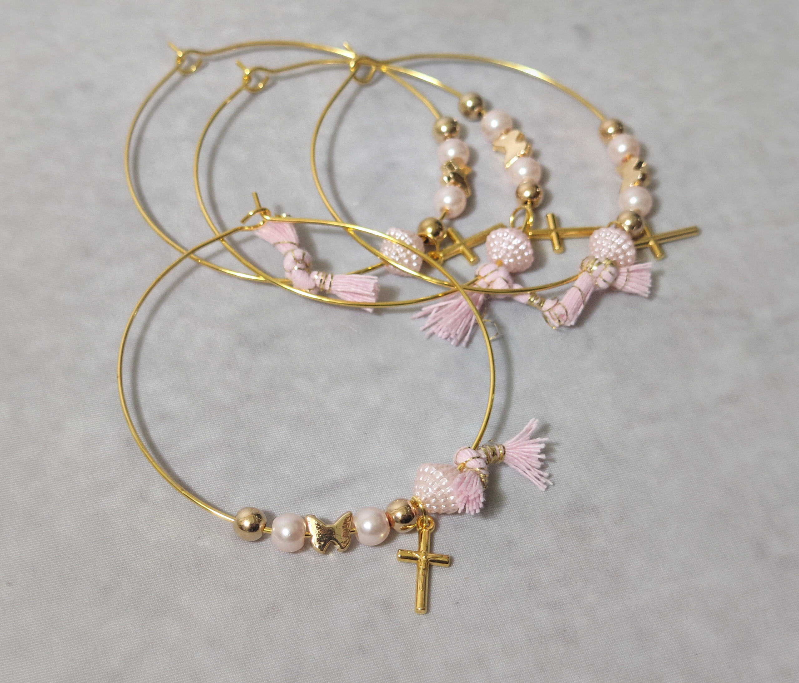 Μαρτυρικά βάπτισης μεταλλικά βραχιόλια στολισμένα με 2 λευκές πέρλες, περίτεχνη ροζ χάντρα 2 χρυσές χάντρες και χρυσή πεταλούδα με μεταλλικό χρυσό σταυρό και δερμάτινο ροζ χειροποίητο φιογκάκι.