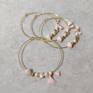 Μαρτυρικά βάπτισης μεταλλικά βραχιόλια στολισμένα με 2 λευκές πέρλες, περίτεχνη ροζ χάντρα  2 χρυσές χάντρες και χρυσό κοχύλι με μεταλλικό χρυσό σταυρό και δερμάτινο ροζ χειροποίητο φιογκάκι.