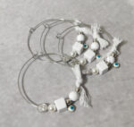 Μαρτυρικά βάπτισης μεταλλικά βραχιόλια στολισμένα με λευκή πέρλα, 2 ασημί χάντρες, τετράγωνη και κυκλική γυαλιστερή χάντρα, ματάκι και χειροποίητο λευκό φιογκάκι.