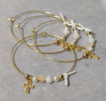 Μαρτυρικά βάπτισης μεταλλικά βραχιόλια στολισμένα με 2 λευκές πέρλες, περίτεχνη λευκή χάντρα  2 χρυσές χάντρες και χρυσή κορώνα με μεταλλικό χρυσό σταυρό και δερμάτινο λευκό φιογκάκι.