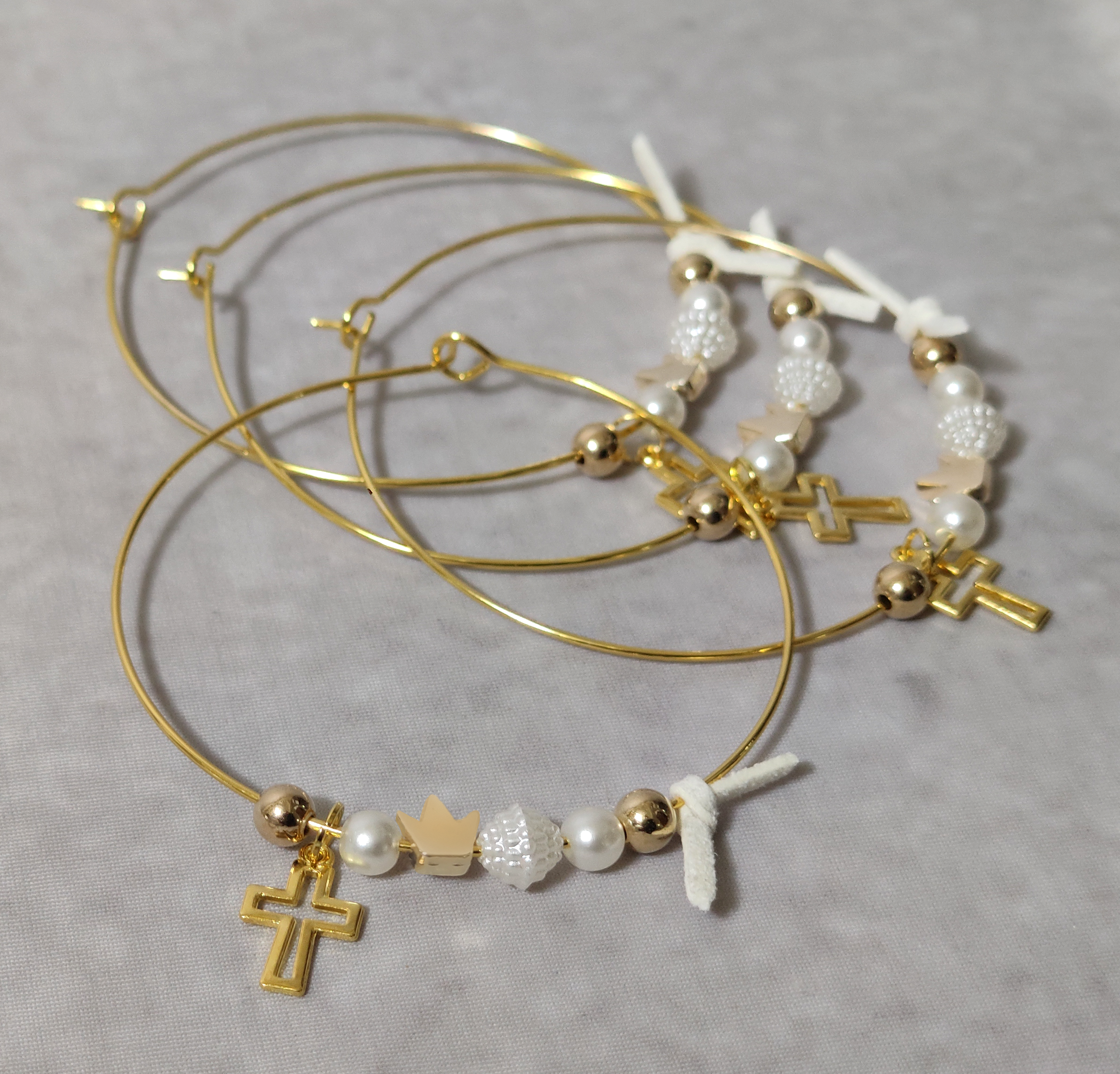 Μαρτυρικά βάπτισης μεταλλικά βραχιόλια στολισμένα με 2 λευκές πέρλες, περίτεχνη λευκή χάντρα 2 χρυσές χάντρες και χρυσή κορώνα με μεταλλικό χρυσό σταυρό και δερμάτινο λευκό φιογκάκι.