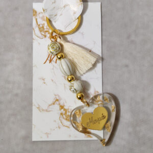 Μαρτυρικά βάπτισης μπρελόκ με λευκές και χρυσές χάντρες, καρδούλα με χάραξη από χρυσό καθρέφτη πλεξι γκλας και διακοσμητικό από υγρό γυαλί με φύλλα χρυσού και καρδιά από χρυσό καθρέφτη πλεξι γκλας.