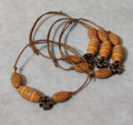 Μαρτυρικά βάπτισης βραχιόλια Boho με  ξύλινες ανάγλυφες χάντρες με μεταλλικό σταυρουδάκι.