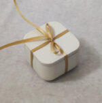 Μπομπονιέρα γάμου μπιζουτιέρα κεραμική σε εκρού χρώμα δεμένη με σατέν κορδέλα.