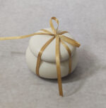 Μπομπονιέρα γάμου κεραμικό μακαρόν 
 σε εκρού χρώμα δεμένη με σατέν κορδέλα.