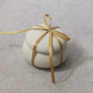 Μπομπονιέρα γάμου κεραμικό μακαρόν 
 σε εκρού χρώμα δεμένη με σατέν κορδέλα.