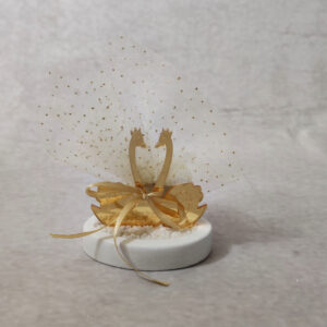 Μπομπονιέρα γάμου κύκνοι από χρυσό καθρέφτη plexi-glass σε βότσαλο.